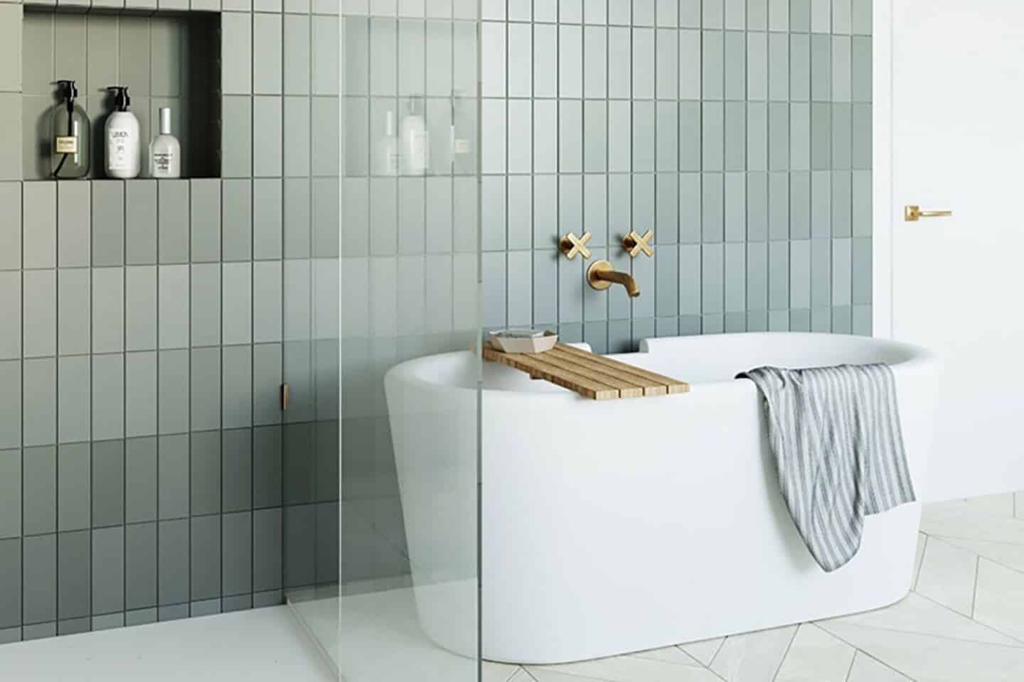 Arielbath freestanding bathtub with grey tiled wall behind.