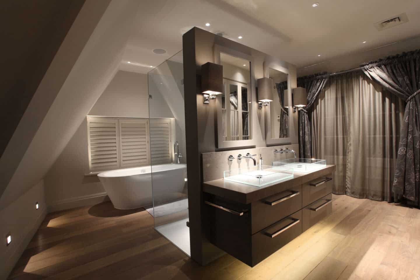 A luxury bathroom with double vanity, double shower and freestanding bath featuring layered lighting scheme by John Cullen Lighting.