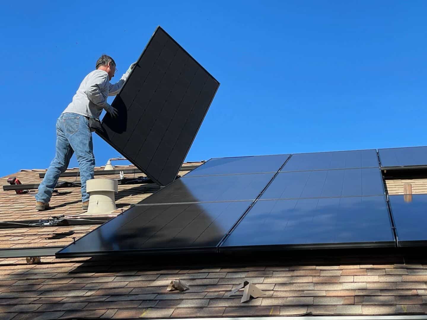 A man installing solar panels on the roof
