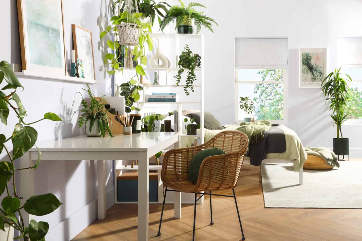 A bedroom that has a small home office in one corner. Plants increase home health