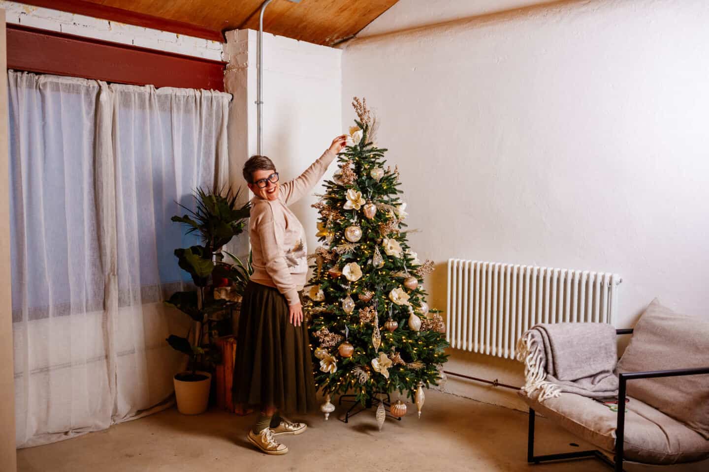 A woman in her forties adds a tree topper to a realistic artificial Christmas tree from Balsam Hill