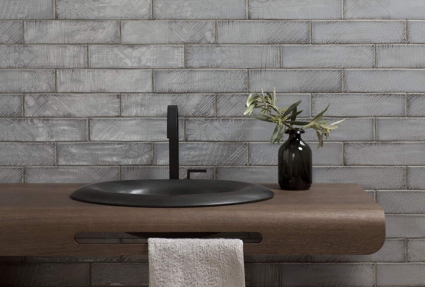 Grey textured tiles in a bathroom with a sink in front