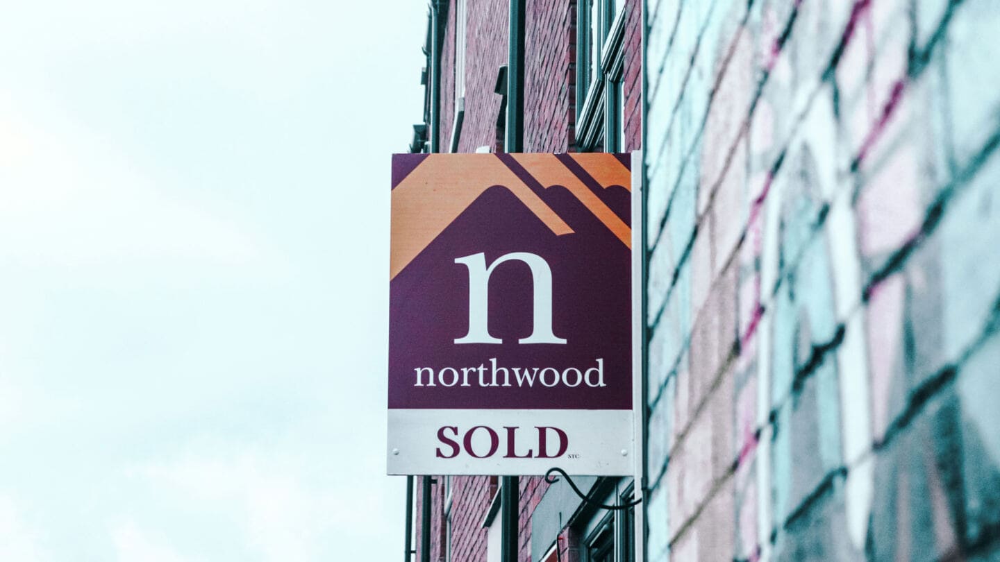 An estate agents sold sign attached to a house