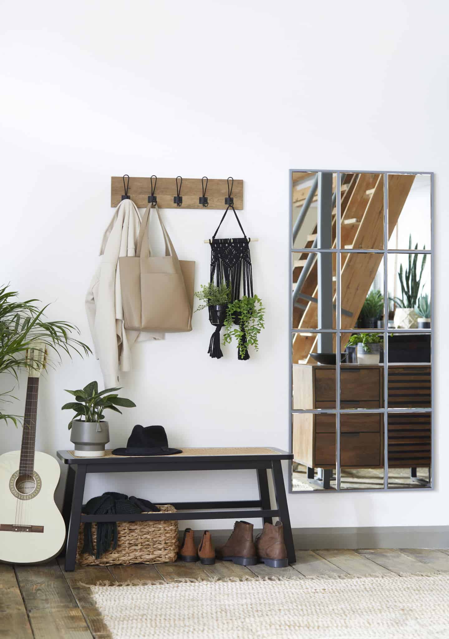 A large window mirror bounces natural light around in this industrial boho hallway