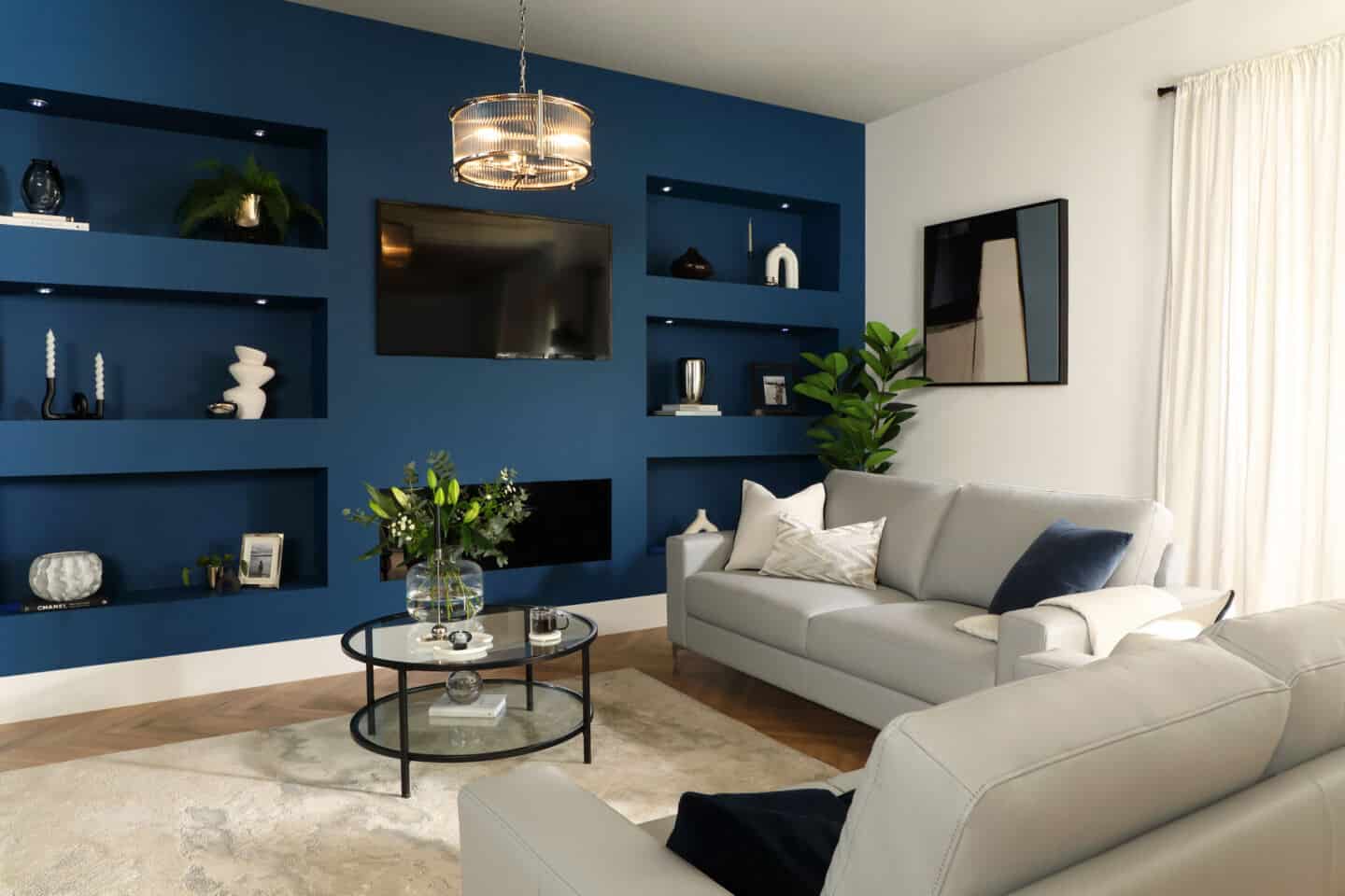 A living room with a navy blue feature wall. The wall has alcoves built into it for storage.