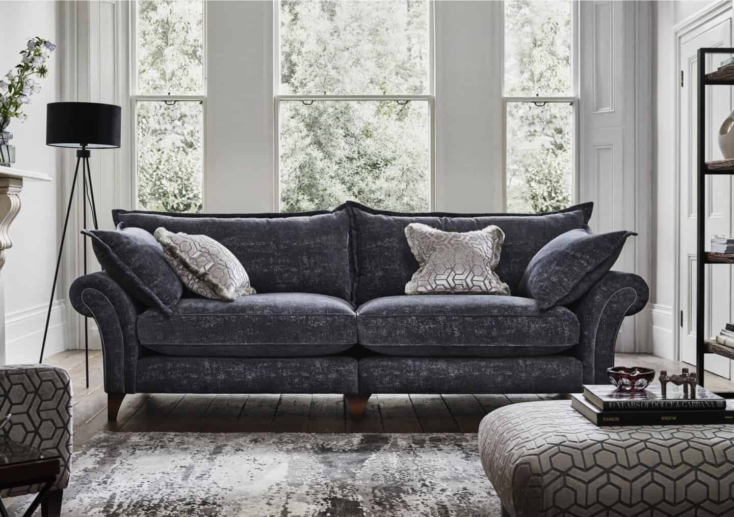 A grey English roll arm sofa with large white sash windows behind