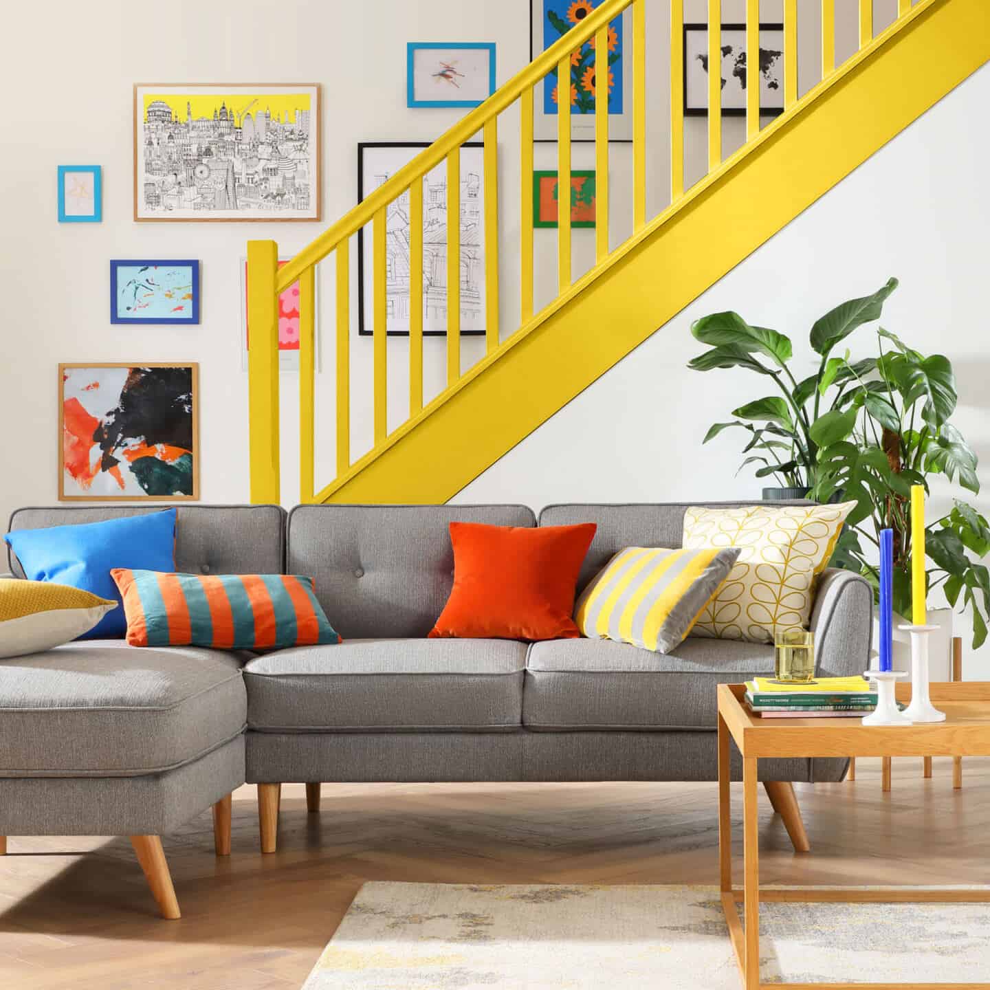 A bright yellow statement staircase in a modern white home. A gallery wall runs up the stairs