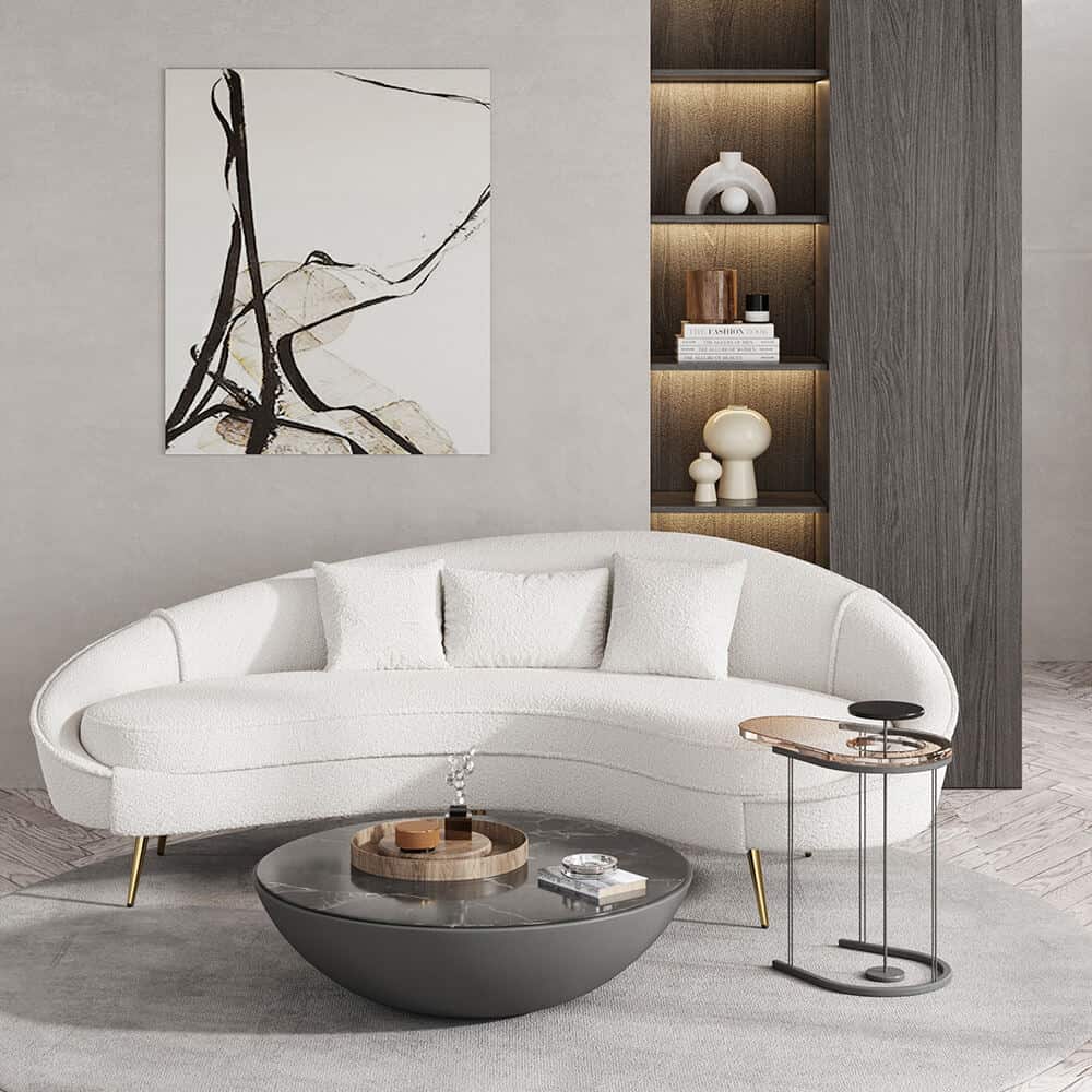 A white curved sofa in bouclé fabric with abstract art on the wall behind and a round marble coffee table in front