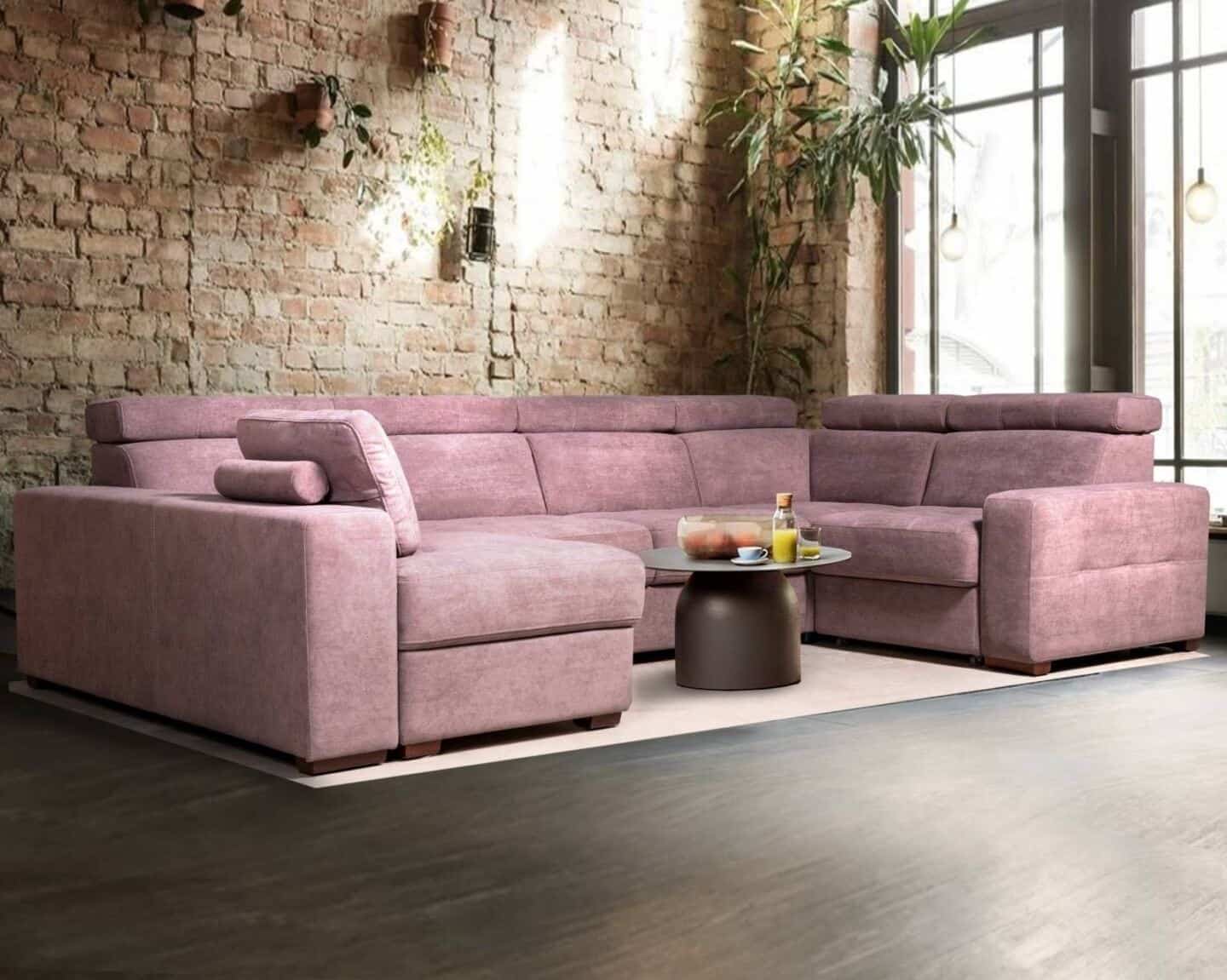 How to choose the perfect sofa for your lifestyle. Modular pink sofa in anfront of an exposed brick wall with plants hung on the wall and a large window to the right.