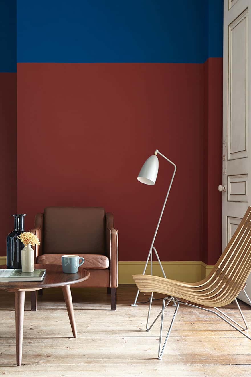 A living room with yellow skirting board, red lower wall and blue upper wall. Image c/o Little Greene