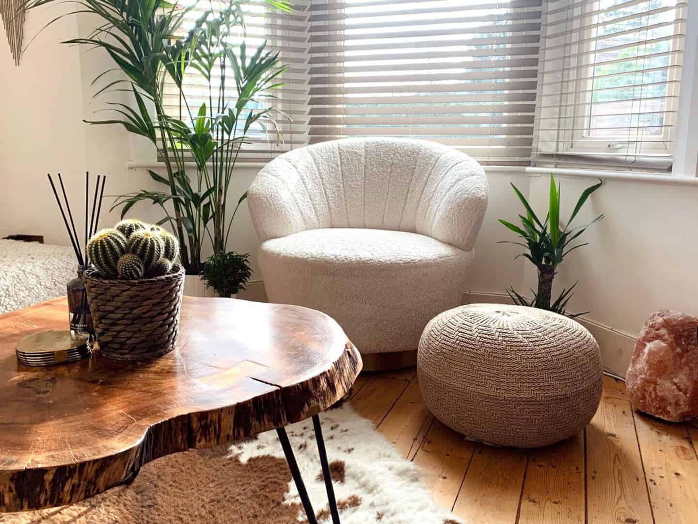 The Penny swivel armchair in bouclé textiles from Cult Furniture. A living room featuring a raw edge coffee table on a cowhide rug next to a seagrass pouf.