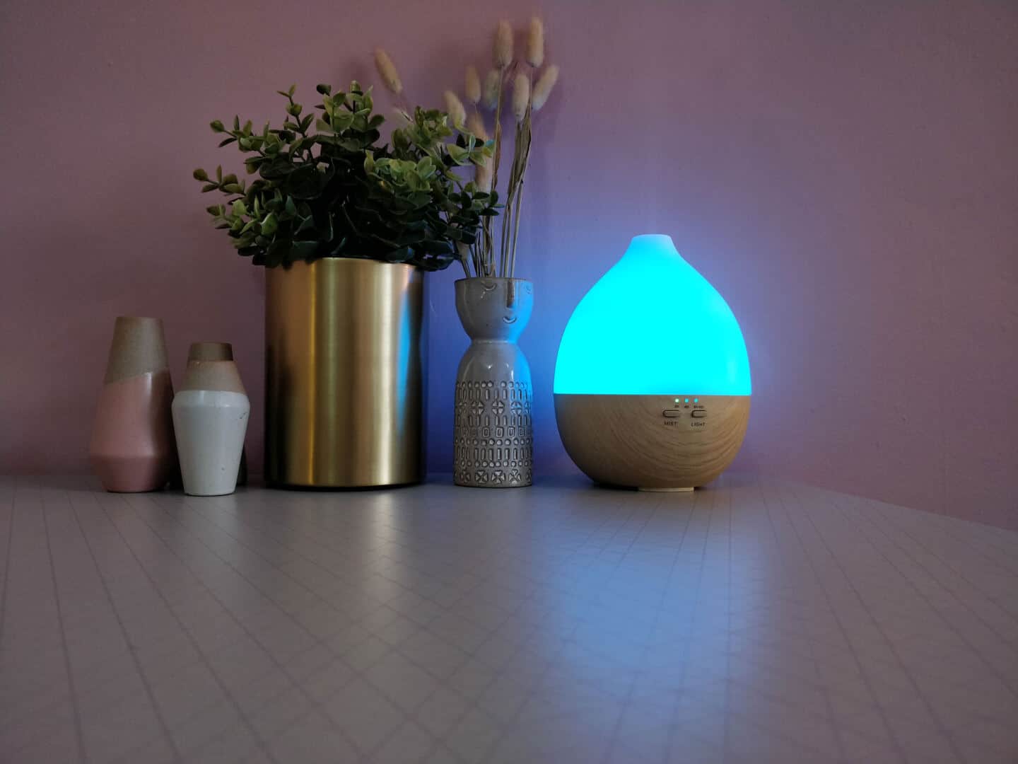 Give your home a spring spruce up by adding scent. An aroma diffuser with light sits on a table next to plants and little vases.