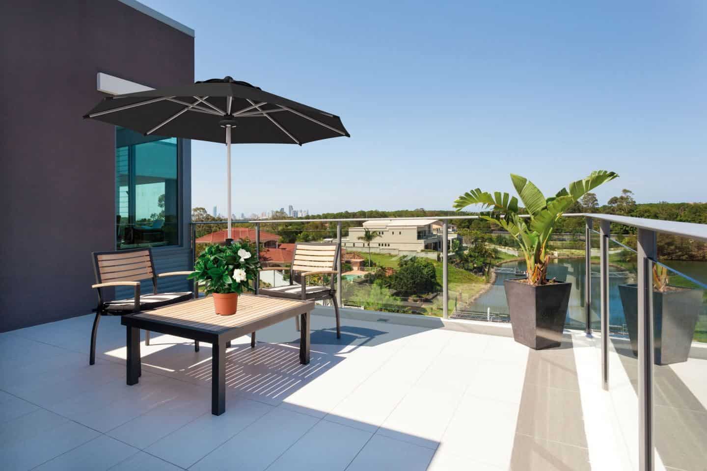 Garden Parasol from Solero Parasols. Large black garden parasol above an outdoor furniture set on a terrace.