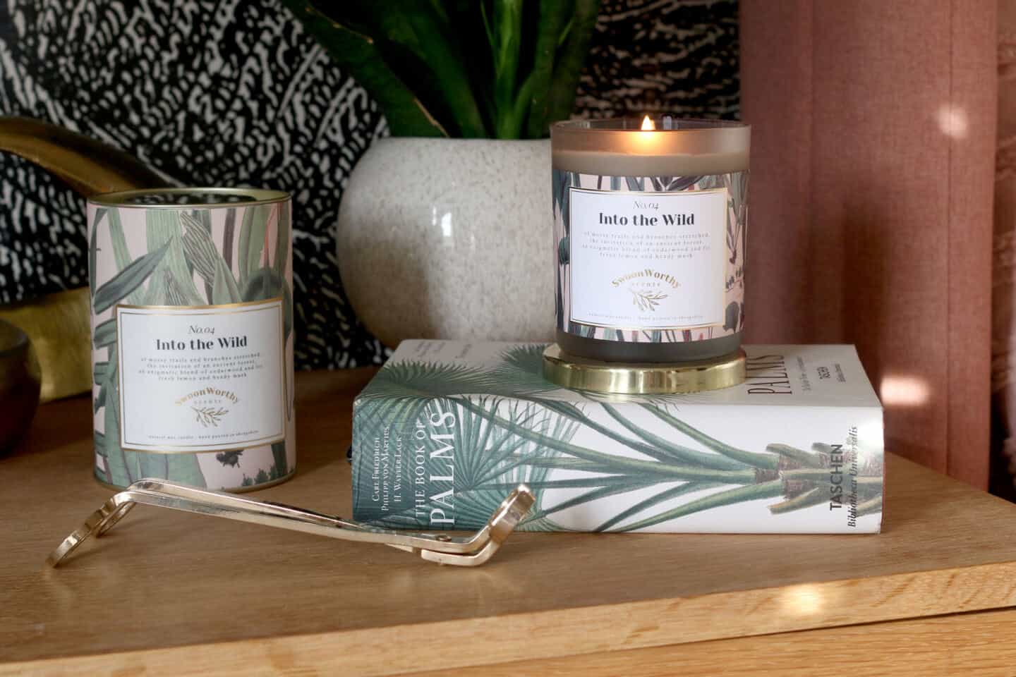 Give your home a Spring Spruce up by lighting scented candles. A beautoful scented candle sits on a book with wick trimmers on the surface in front.