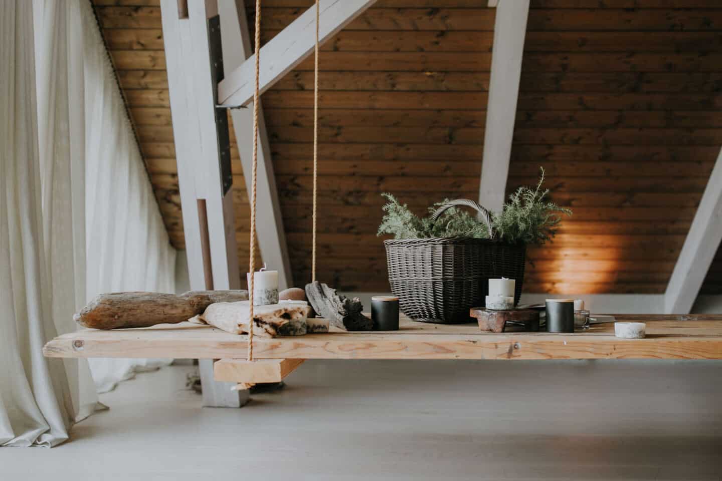 Textured Lives. Using texture in interiors to bring your home to life. Candles and a basket of moss displayed on a wooden swing in a loft room.