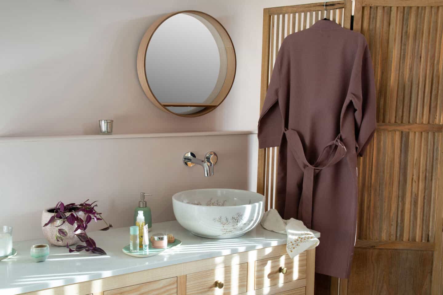 A round white bathroom sink with vanity. The sink is covered in delicate blossom pattern and rests on a countertop in a Japanandi style bathroom