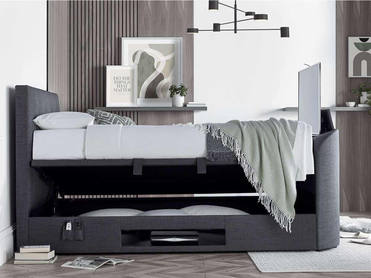 A bedroom with wood panelling in the walls. It features a grey side-opening linen ottoman bed with integrated TV in the footer.