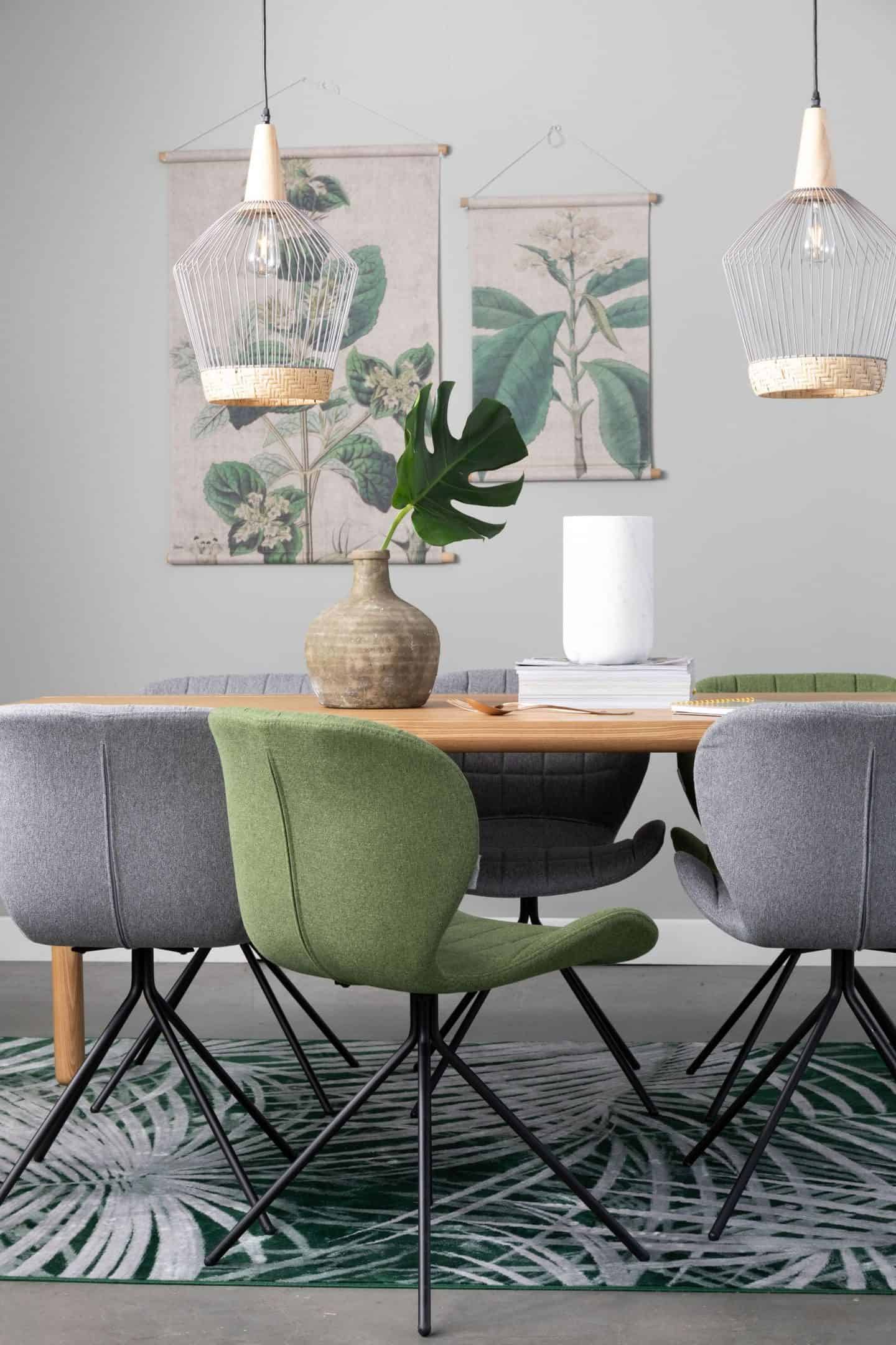 A desk or dining table with chairs around and two pendant lights suspended above. Botanical prints hang on the wall behind.